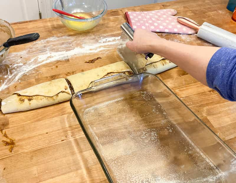 Now that the dough is rolled up, use your greased pan as a guide and cut the loaf into three or four pieces.  Whatever size will fit snugly in your pan.  Place the rolls into your prepared pan, seam side down.